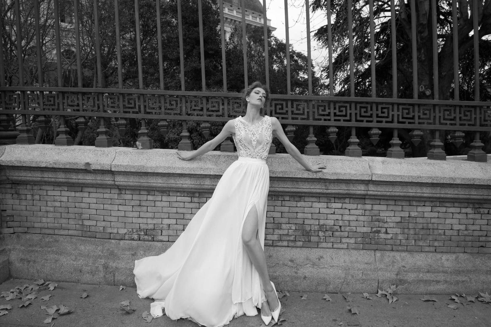 Bride by a park fence, beaded gown with slit