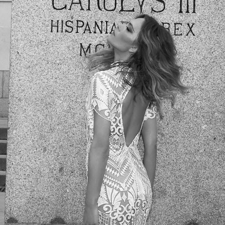 Bride against a carved stone wall, geometric lace gown